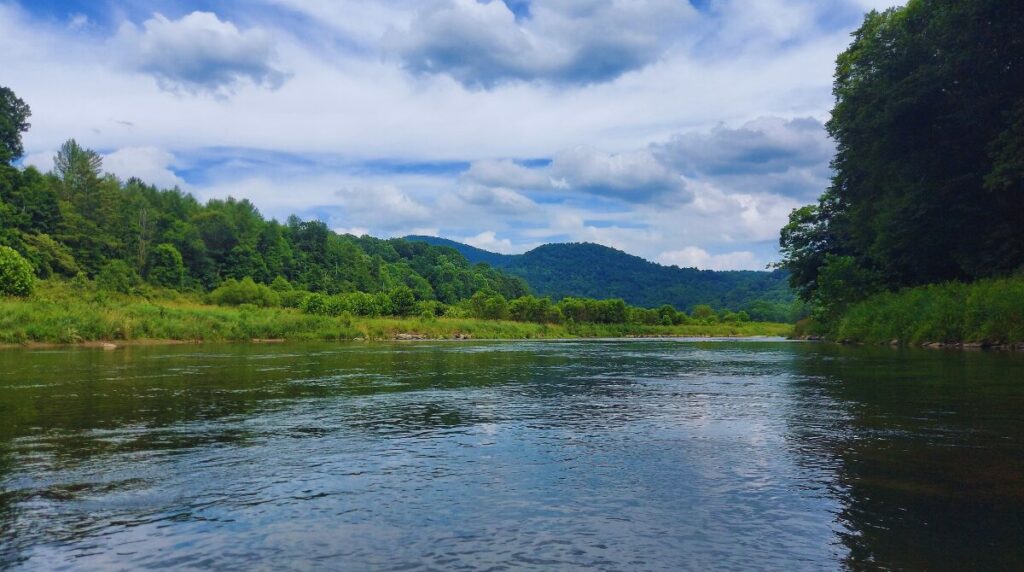 mountains in the background a tree lined bend in the new river in the foreground